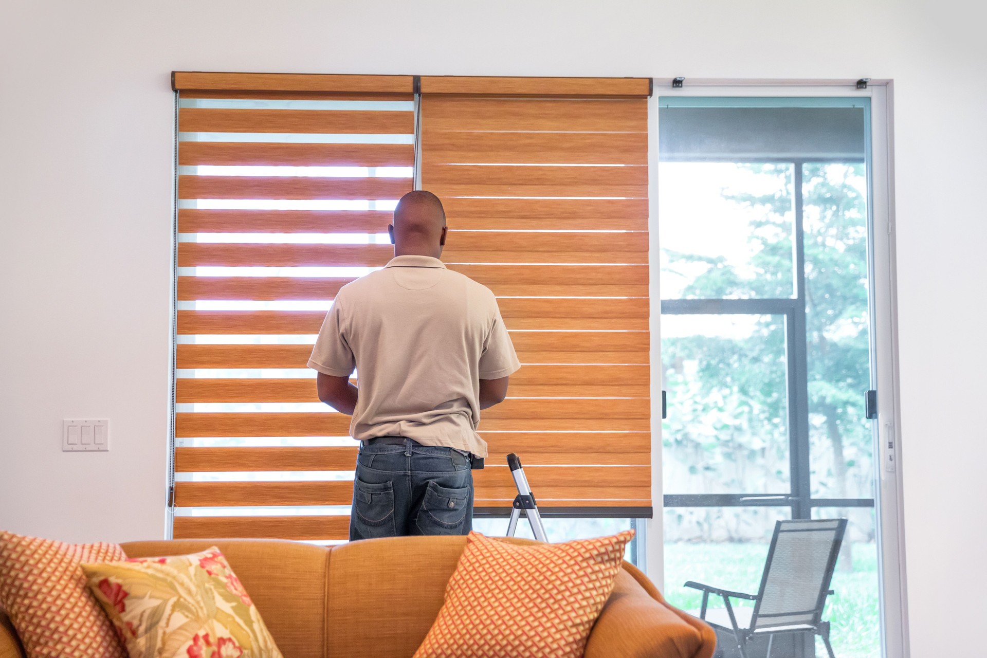Window treatment installer installs shades in a livingroom